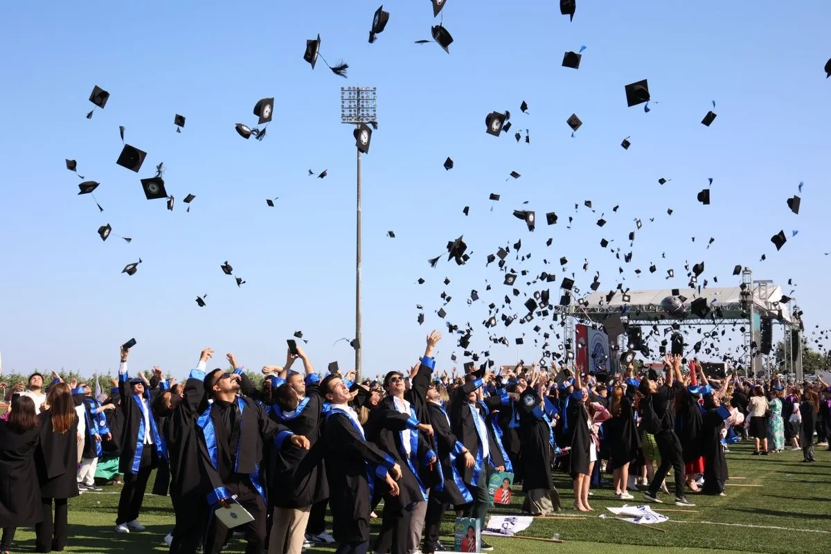“NKÜ 2024-2025 önlisans mezuniyet töreninde öğrenciler sahnede kep atarken”